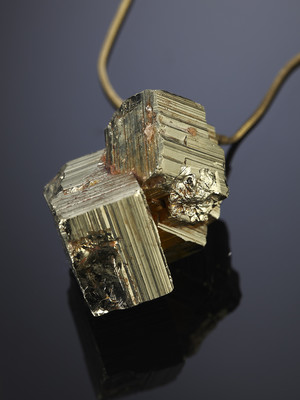 Kubischer Pyritkristall auf einer Bronzeschnur
